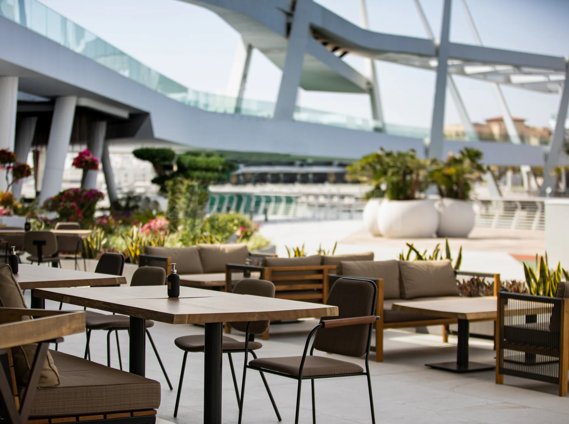 Rooftop terrace at Tazal Restaurant Abu Dhabi featuring outdoor seating, large white planters, and a modern steel-and-glass