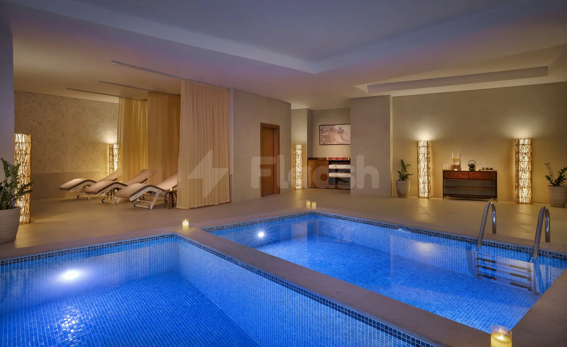Indoor swimming pool at Zoya Health & Well-Being Resort in Ajman, featuring blue mosaic tiles and a stainless steel