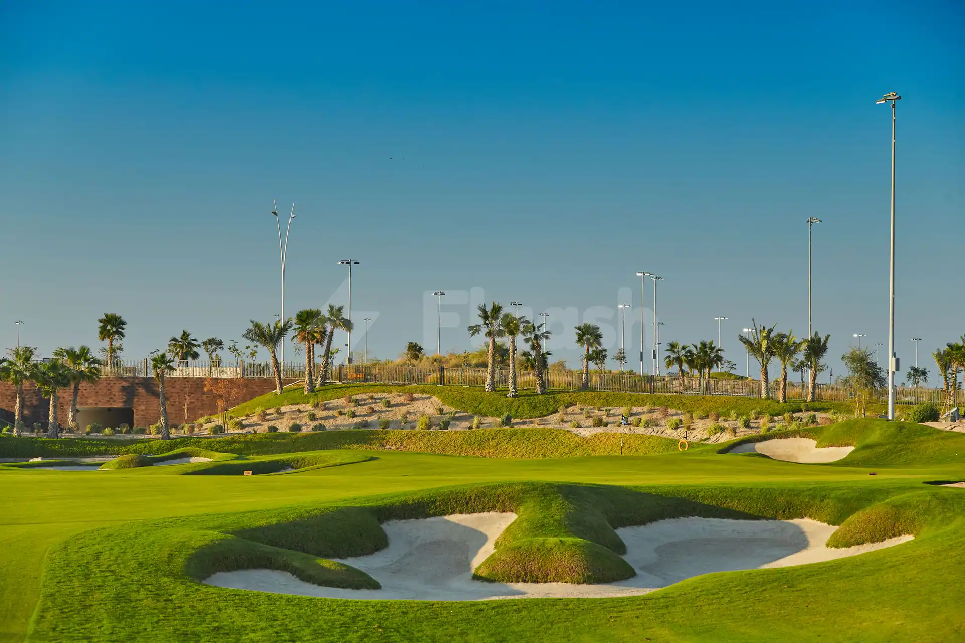 Golf course at Yas Acres Golf & Country Club in Abu Dhabi featuring sand bunkers and palm trees