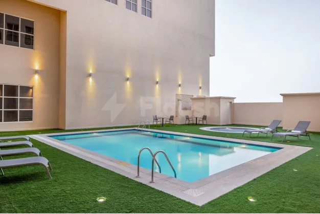 Rectangular swimming pool at Residence Inn Dammam in Dammam with blue water, a metal ladder, and artificial grass