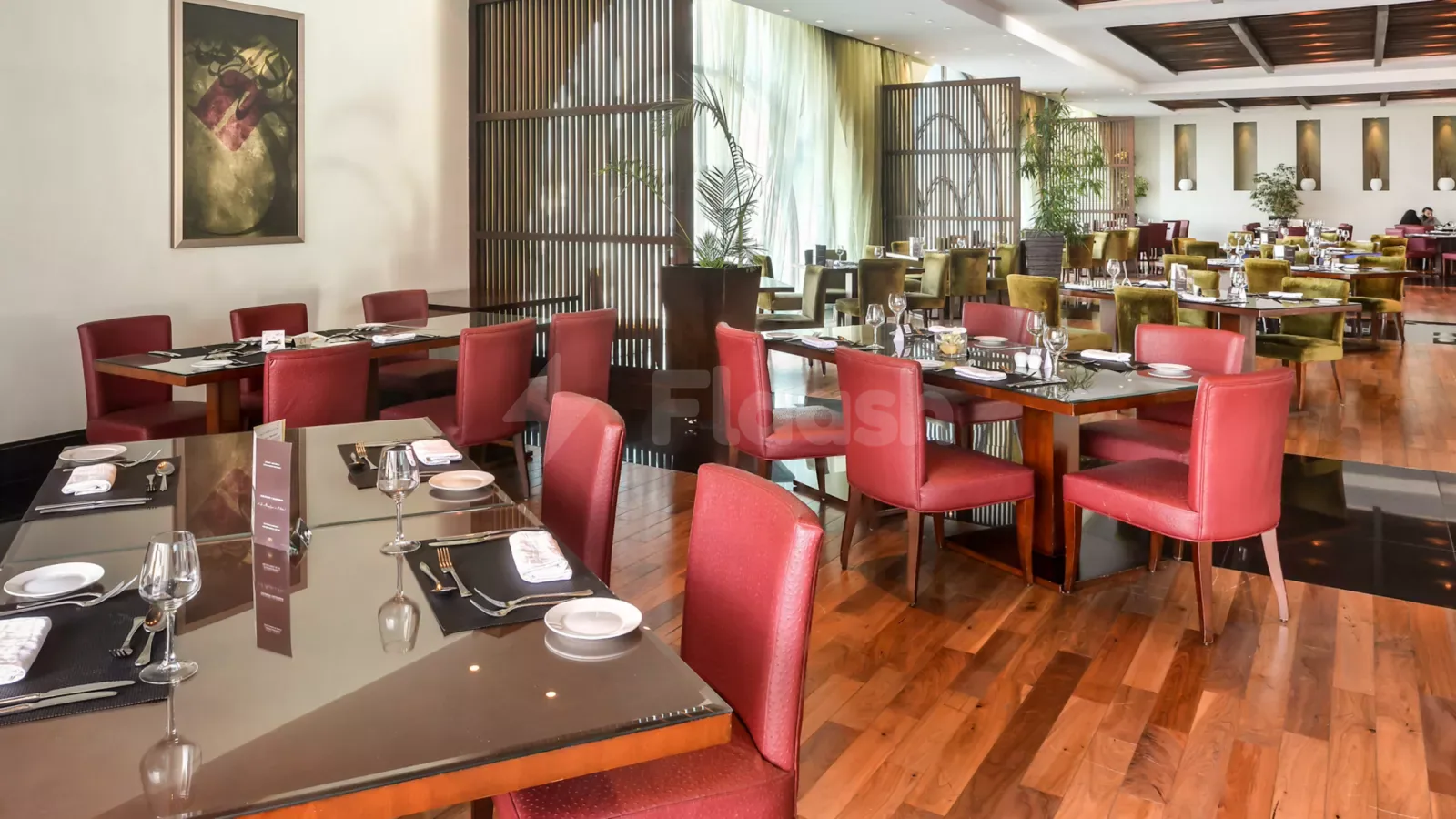Restaurant at Sofitel Al Khobar The Corniche featuring glass-topped dining tables, red and green upholstered chairs