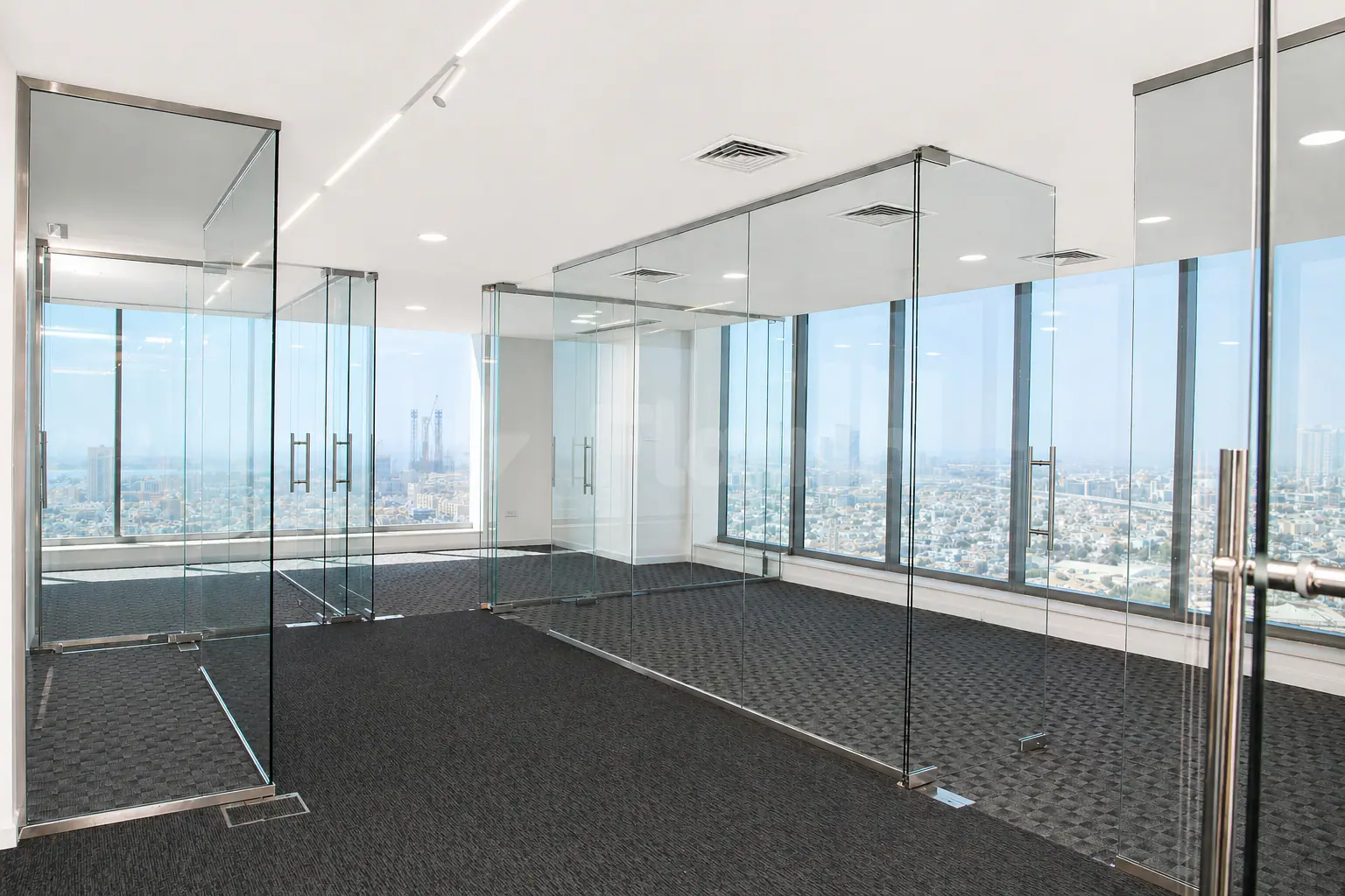 Meeting room at The H Hotel Dubai with glass partition walls and floor-to-ceiling windows offering a city