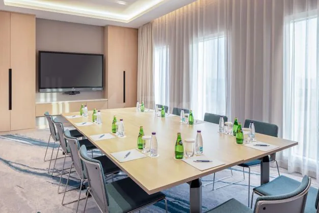 Boardroom at Four Points By Sheraton Jeddah featuring a long wooden table, grey chairs, green bottles