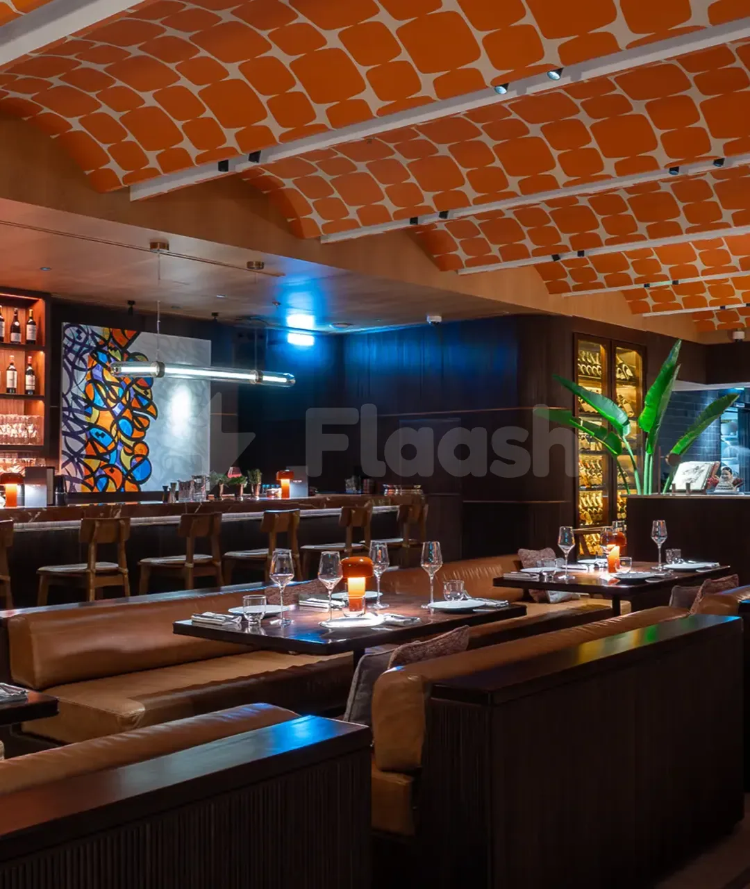 Restaurant interior at Chez Wam in Dubai featuring an orange patterned ceiling and dark wooden walls with leather