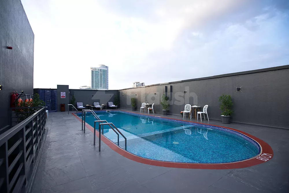 Rooftop swimming pool at Fortis Hotel Fujairah with blue mosaic tiles, red tile border, and grey stone flooring