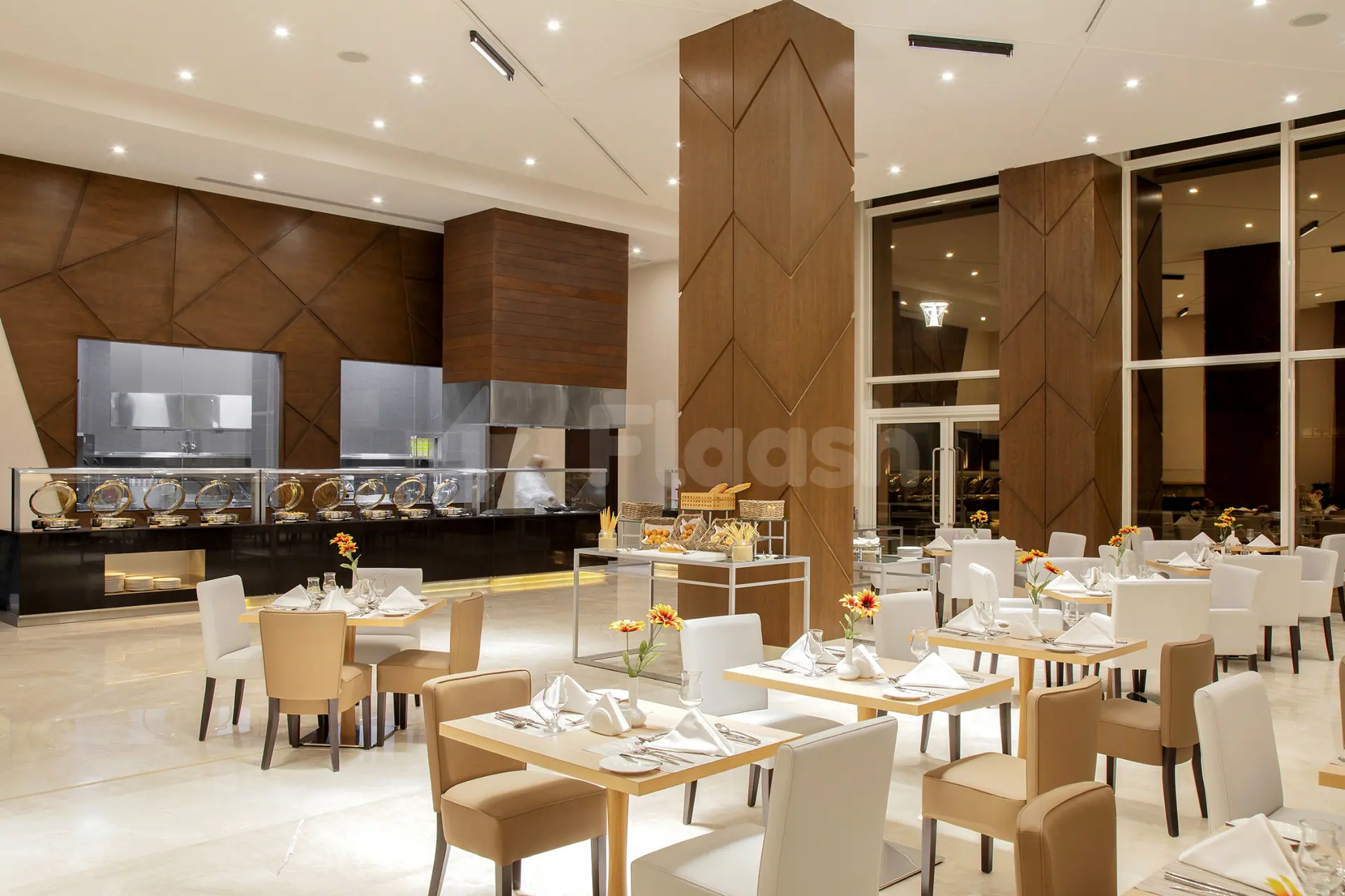 Restaurant at Cristal Amaken Hotel Riyadh featuring an open kitchen with stainless steel counters and geometric wooden wall
