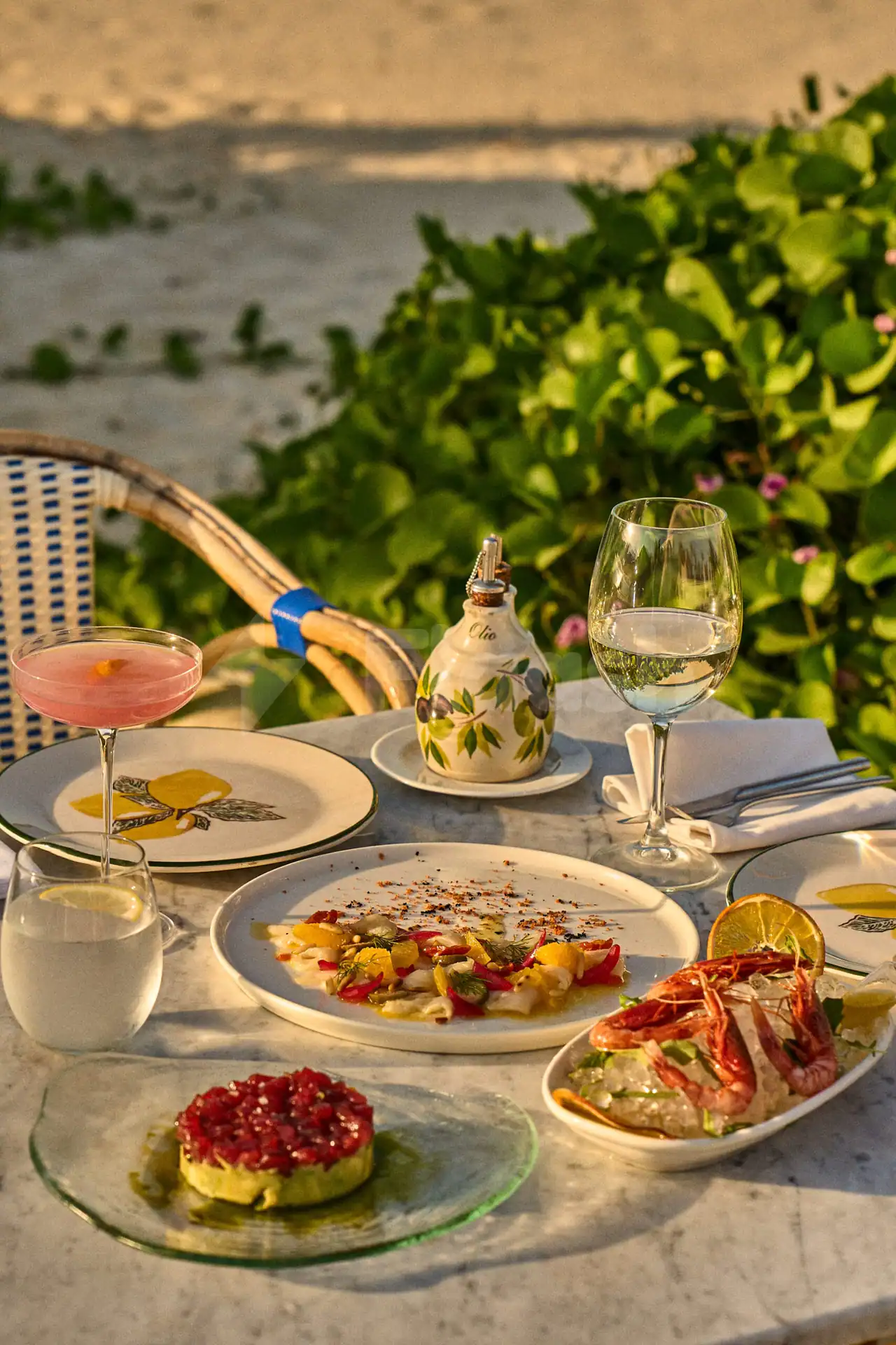 Outdoor dining setup at Lucia's Mare Restaurant Dubai featuring a marble table with seafood dishes and green leafy