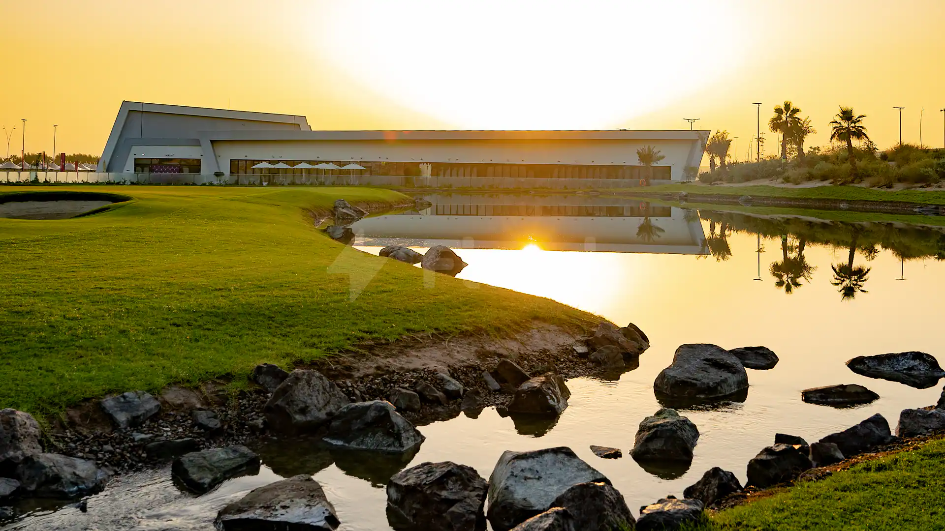 Park at Yas Acres Golf & Country Club in Abu Dhabi with a still pond reflecting sunset light