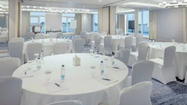 Ballroom at Four Points By Sheraton Jeddah featuring round tables with white linens, white chair covers, and large