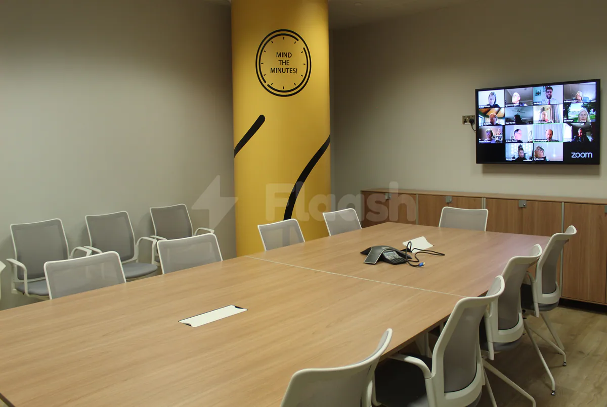 Boardroom at Workaholics Qatar in Doha with yellow accent wall and Zoom video call display