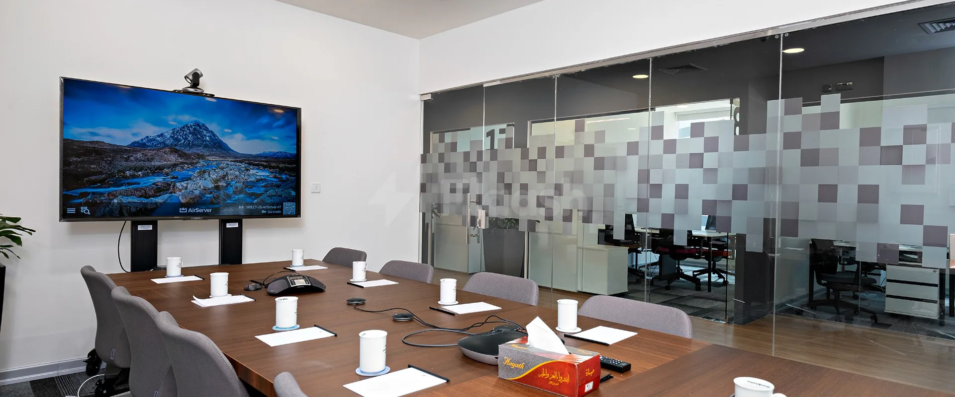Boardroom at Nestwork Burj Alfardan Lusail featuring a long wooden table, grey chairs, and a mounted TV