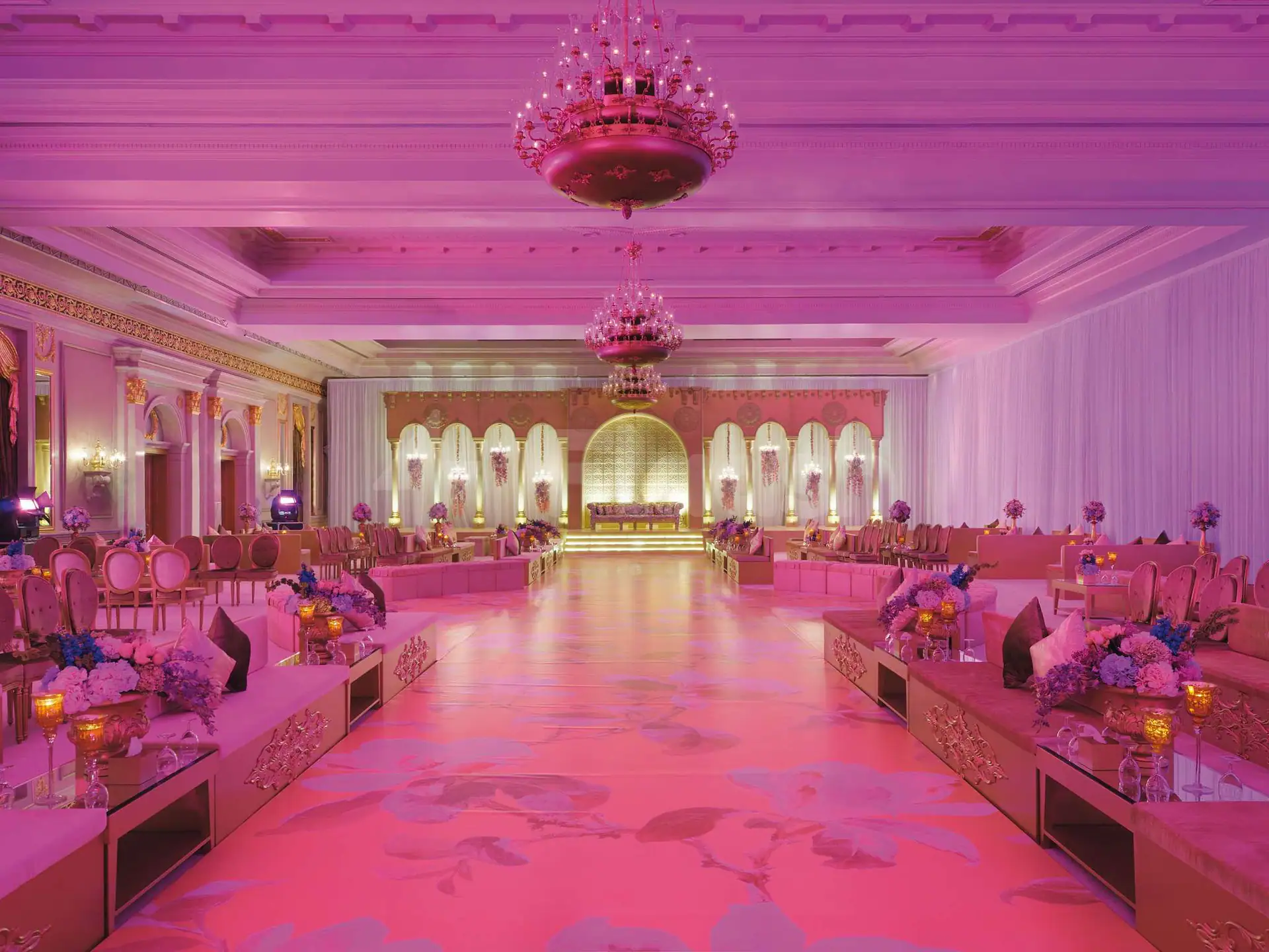Ballroom at Movenpick Hotel AlKhobar in Dammam featuring pink ambient lighting, ornate chandeliers, and a floral-patterned floor