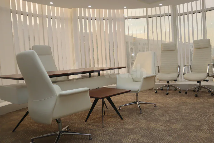 Boardroom at Tejwaans Business Centre in Doha featuring white leather chairs, a dark wooden table, and curved windows