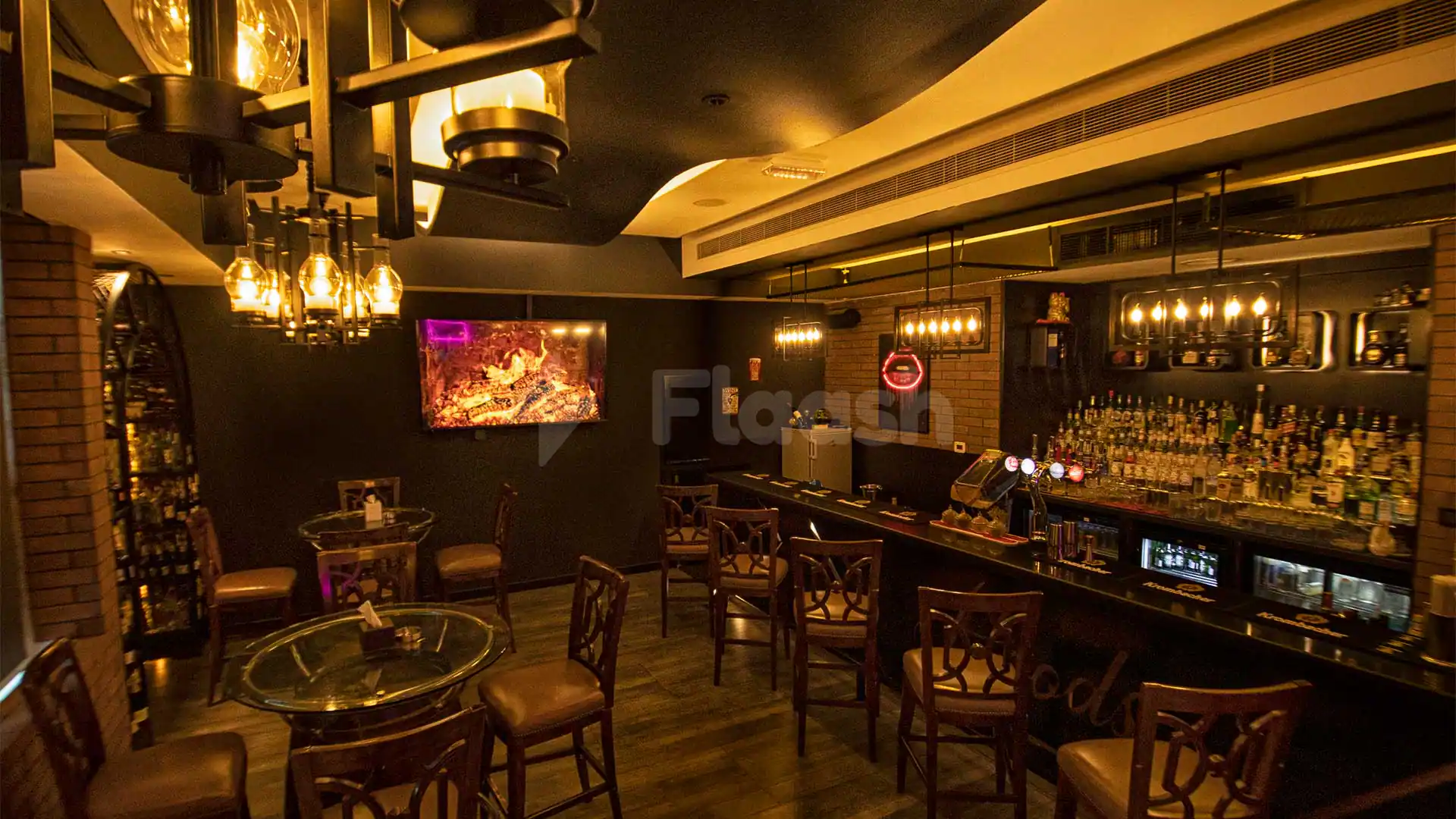 Bar counter at Hoods Resto & Bar in Abu Dhabi with hanging pendant lights and a fireplace display