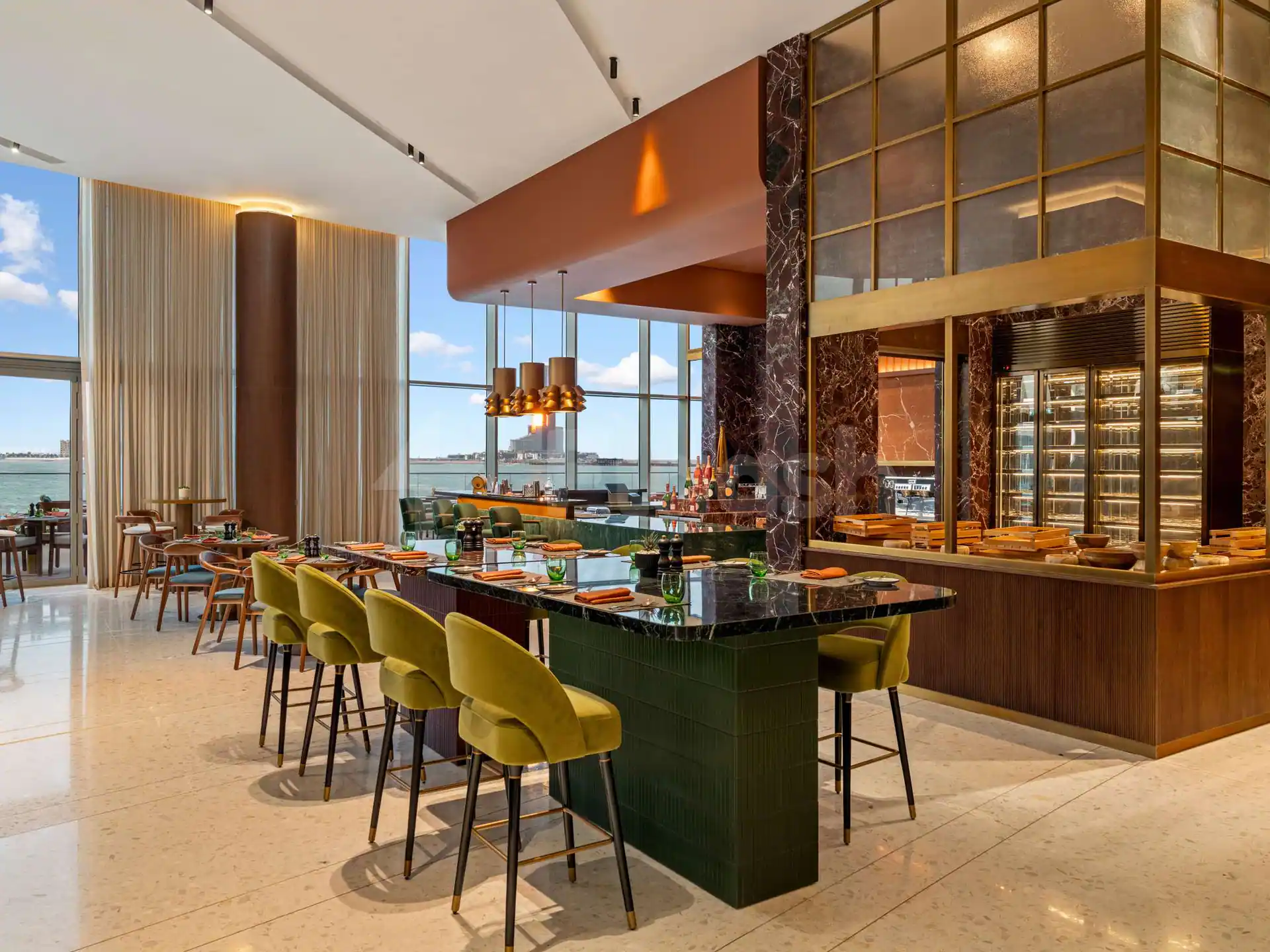 Restaurant at SO Ras Al Khaimah Hotel & Resort featuring a green-tiled bar with black marble countertop