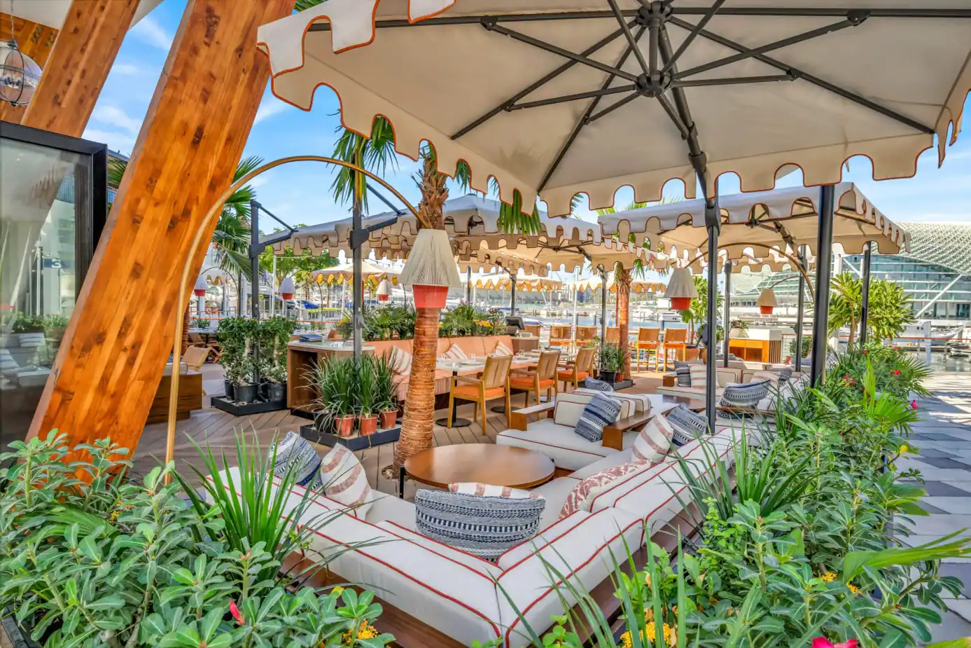 Rooftop terrace at Mika Restaurant Abu Dhabi featuring white cushioned sofas with red trim and large beige umbrellas