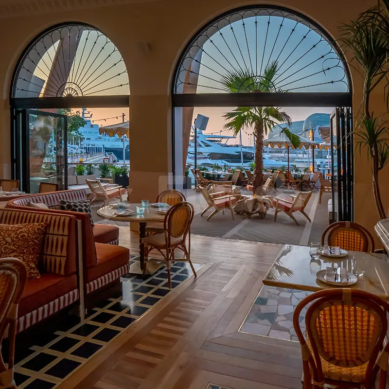 Arched glass doors open to Mika Restaurant Abu Dhabi’s interior with wooden floors, black-and-white tiles