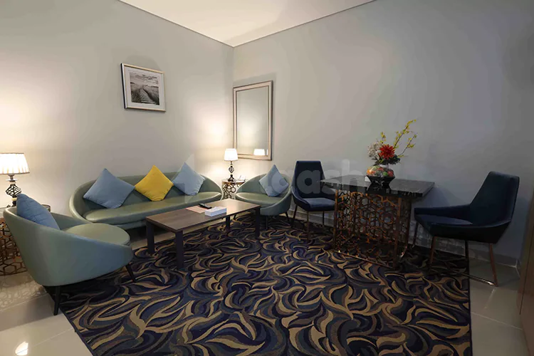 Meeting room at Fortis Hotel Fujairah featuring a green sofa, blue and yellow cushions, and a patterned carpet