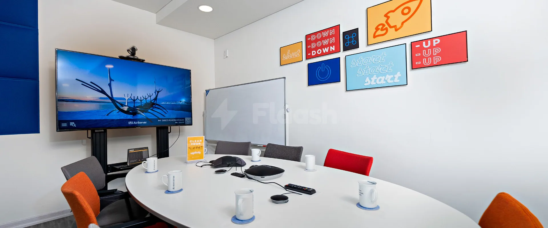 Boardroom at Nestwork Burj Alfardan Lusail featuring a large wall-mounted TV and colourful framed motivational posters on white