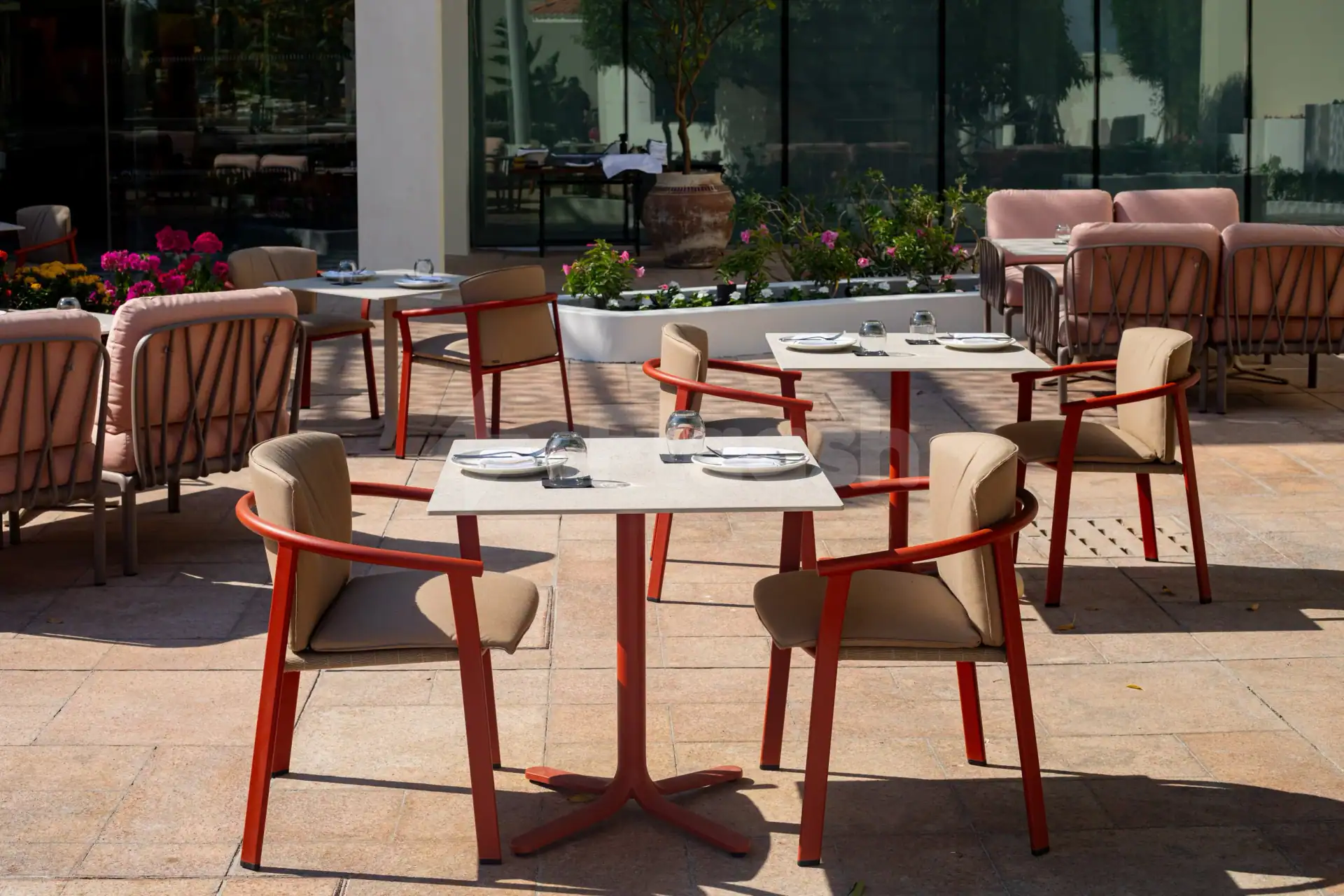 Rooftop terrace at Taparelle Restaurant in Abu Dhabi with square stone tables and potted pink flowers