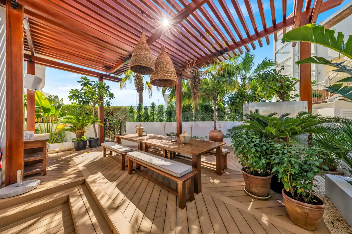 Rooftop terrace at Mika Restaurant Abu Dhabi featuring a wooden pergola, long dining table with benches, and potted