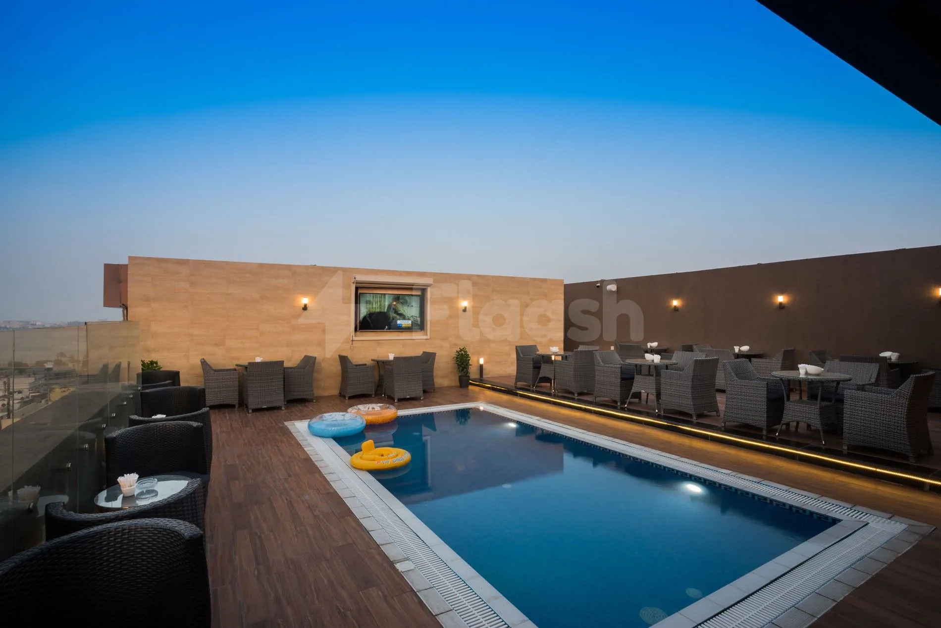 Rooftop terrace at Naviti By Warwick Dammam featuring a rectangular swimming pool with inflatable rings and modern wicker