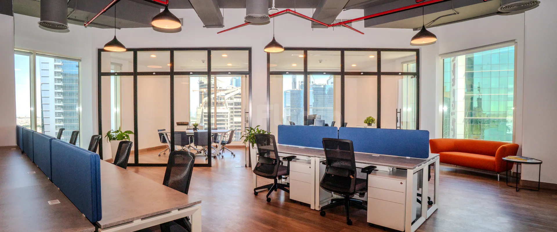 Open plan meeting room at Nestwork Msheireb in Doha featuring blue fabric partitions, black mesh chairs, and large