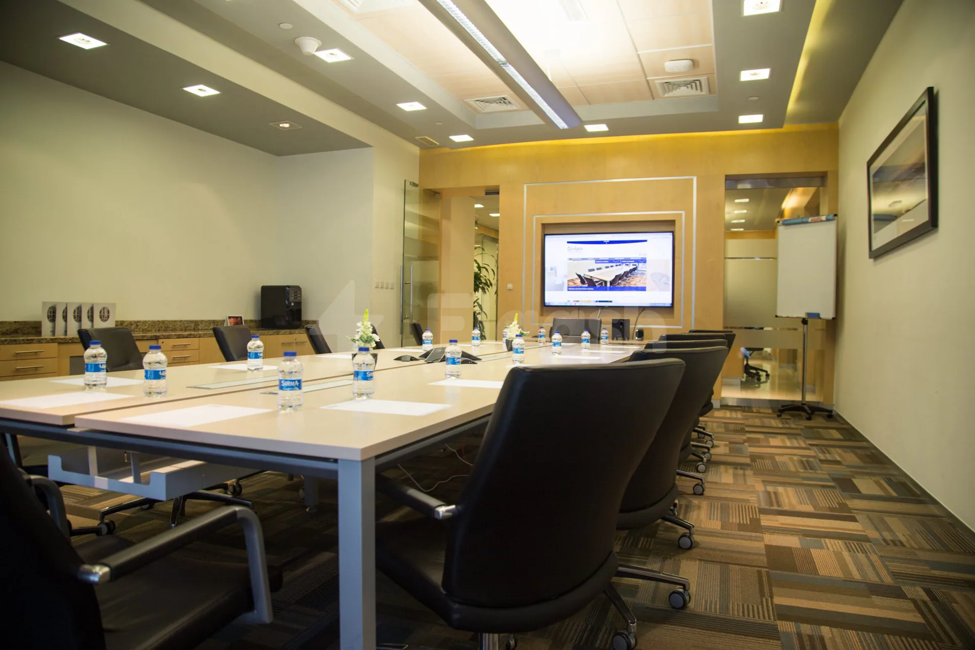 Boardroom at Globex Business Centre Doha with long table, black chairs, mounted screen, and yellow accent wall