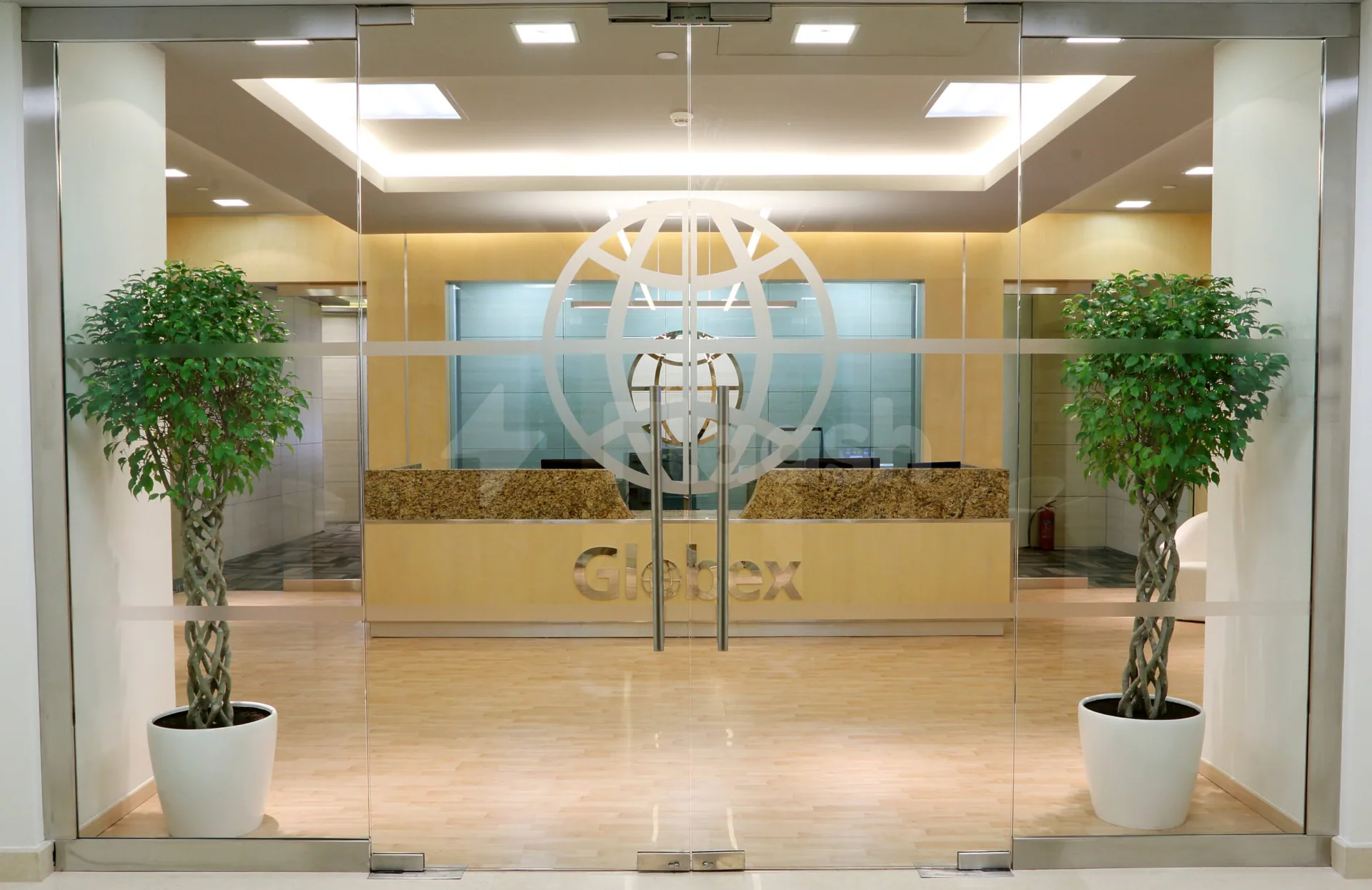 Entrance hall at Globex Business Centre Doha with glass double doors and twisted-trunk potted trees