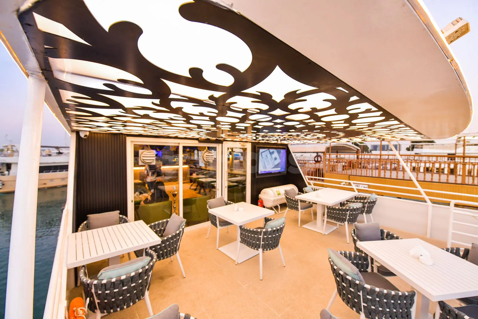 Terrace at Royal Yacht Restaurant in Abu Dhabi featuring a perforated metal ceiling with backlit panels and outdoor