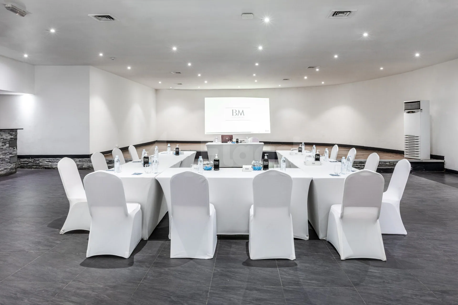 Boardroom at BM Beach Resort Ras Al Khaimah with U-shaped white table setup, projector screen displaying logo