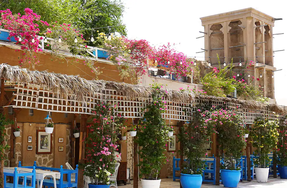 Rooftop terrace at Arabian Tea House Restaurant & Cafe Sharjah featuring a thatched roof, wooden lattice structure, and pink