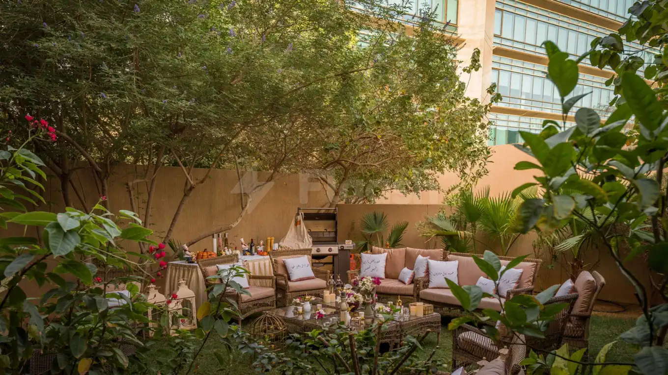 Terrace at Vivienda Hada Residences in Riyadh featuring wicker seating, an outdoor grill, and lush greenery with pink