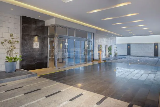 Entrance hall at Four Points By Sheraton Jeddah featuring glass doors, a black marble wall, and a striped