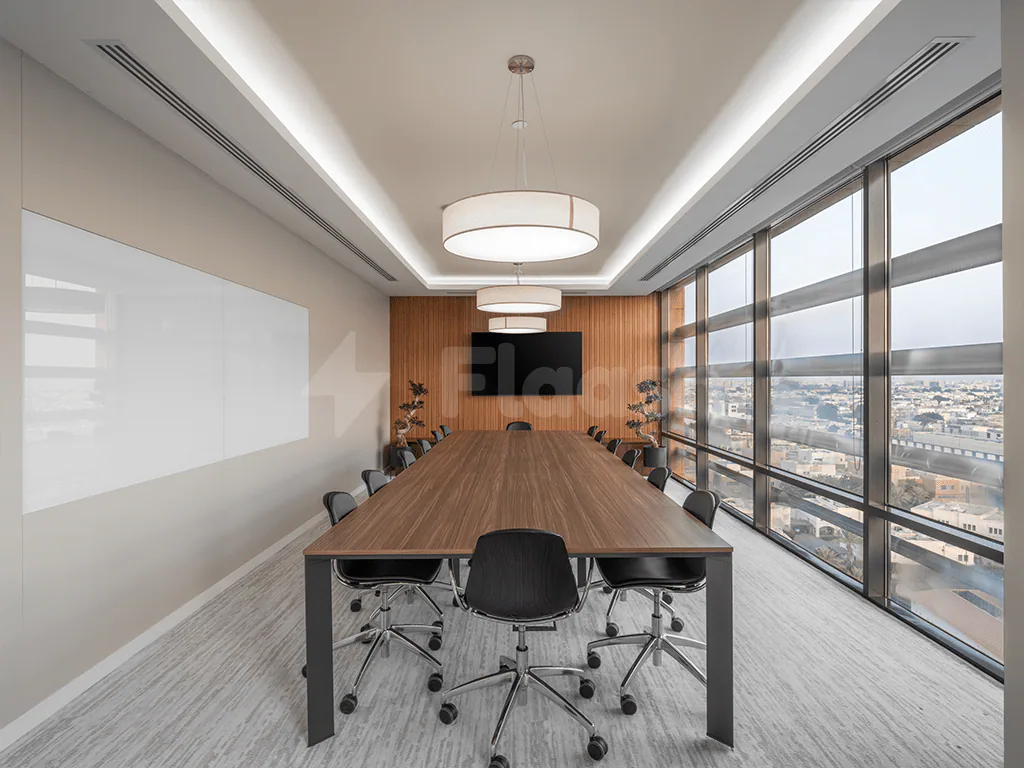 Boardroom at Gravita Coworking Space Jeddah featuring a long wooden table, black rolling chairs, and floor-to-ceiling windows