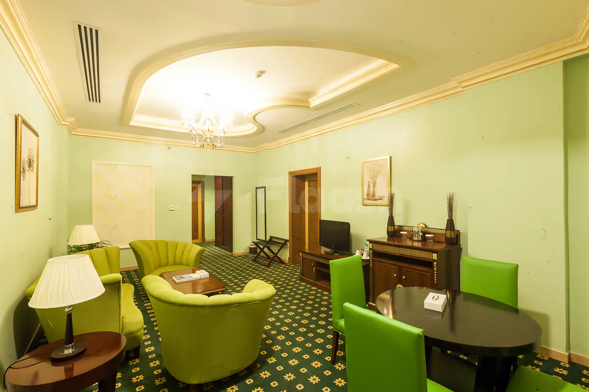 Meeting room at Sahara Beach Resort & Spa in Sharjah featuring green armchairs, a dark wooden table, and ornate