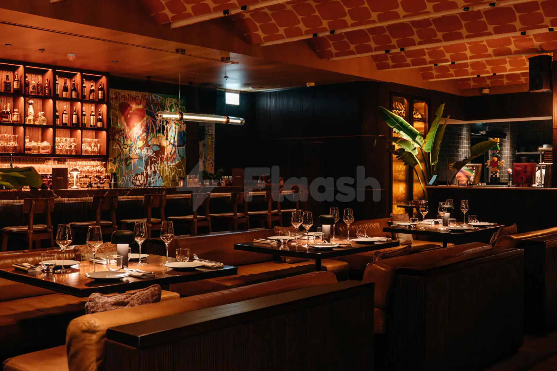 Restaurant interior at Chez Wam in Dubai featuring brown leather booths, dark wooden tables, and a vibrant graffiti