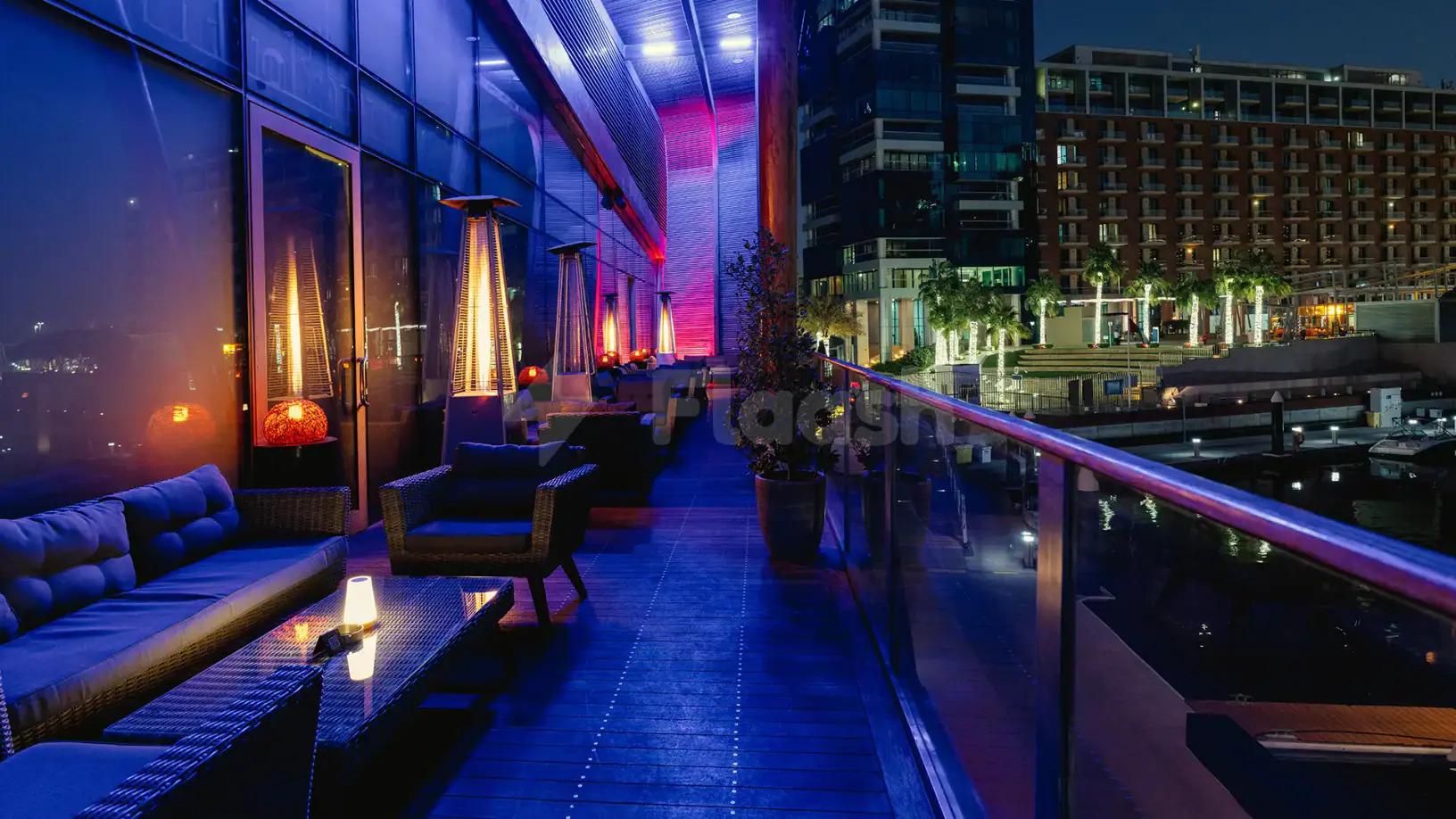 Rooftop terrace at Ornina Arabian Lounge in Abu Dhabi featuring a glass railing, ambient lighting, and a marina