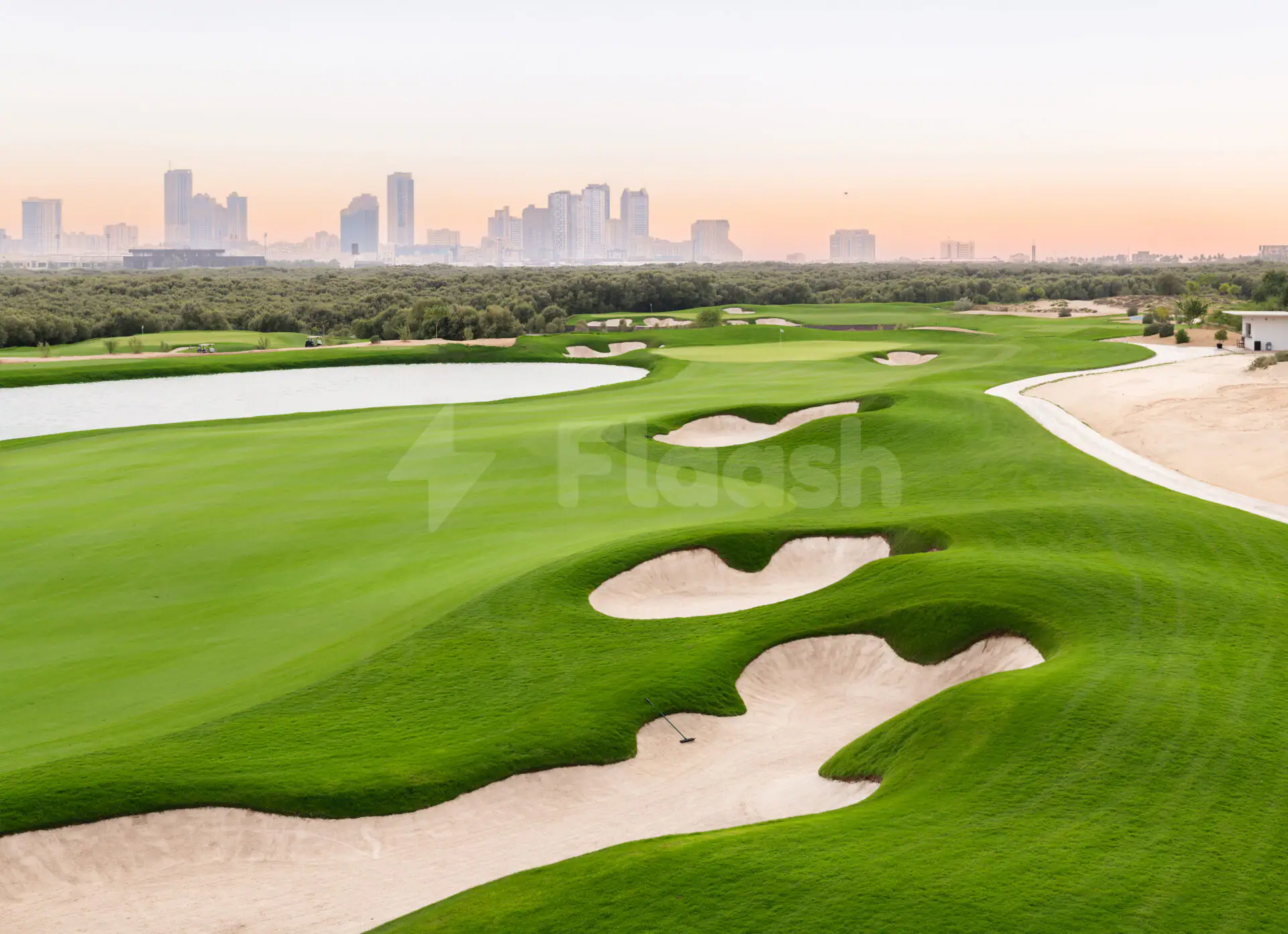 Golf course at Al Zorah Golf Club in Ajman with sand bunkers and distant city skyline