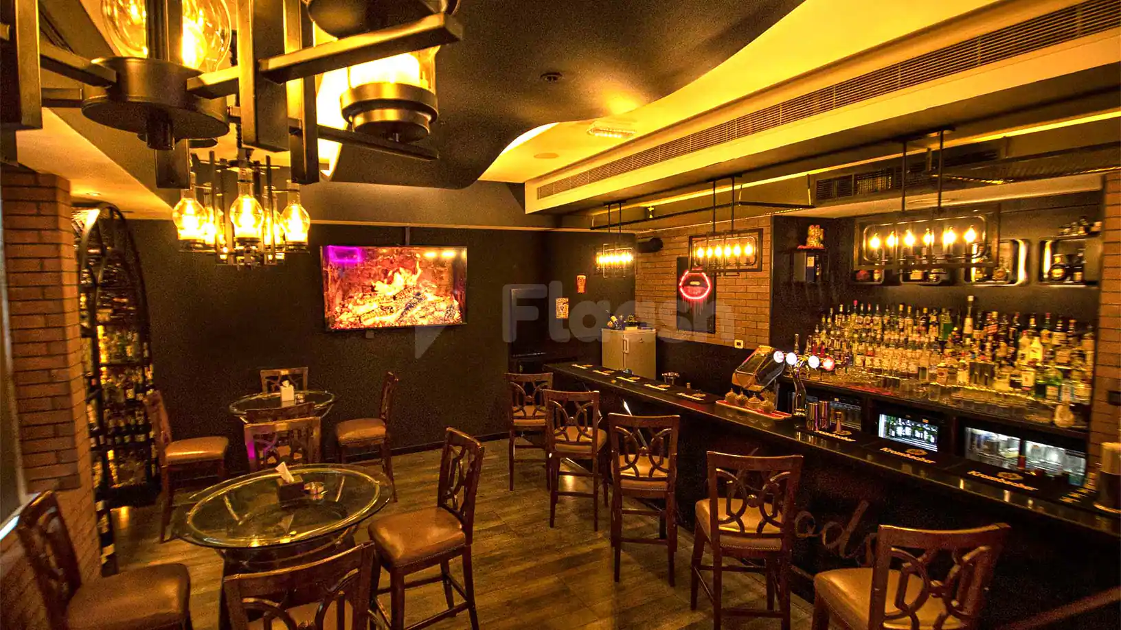 Bar counter at Hoods Resto & Bar in Abu Dhabi, featuring a brick wall backdrop and a neon lip