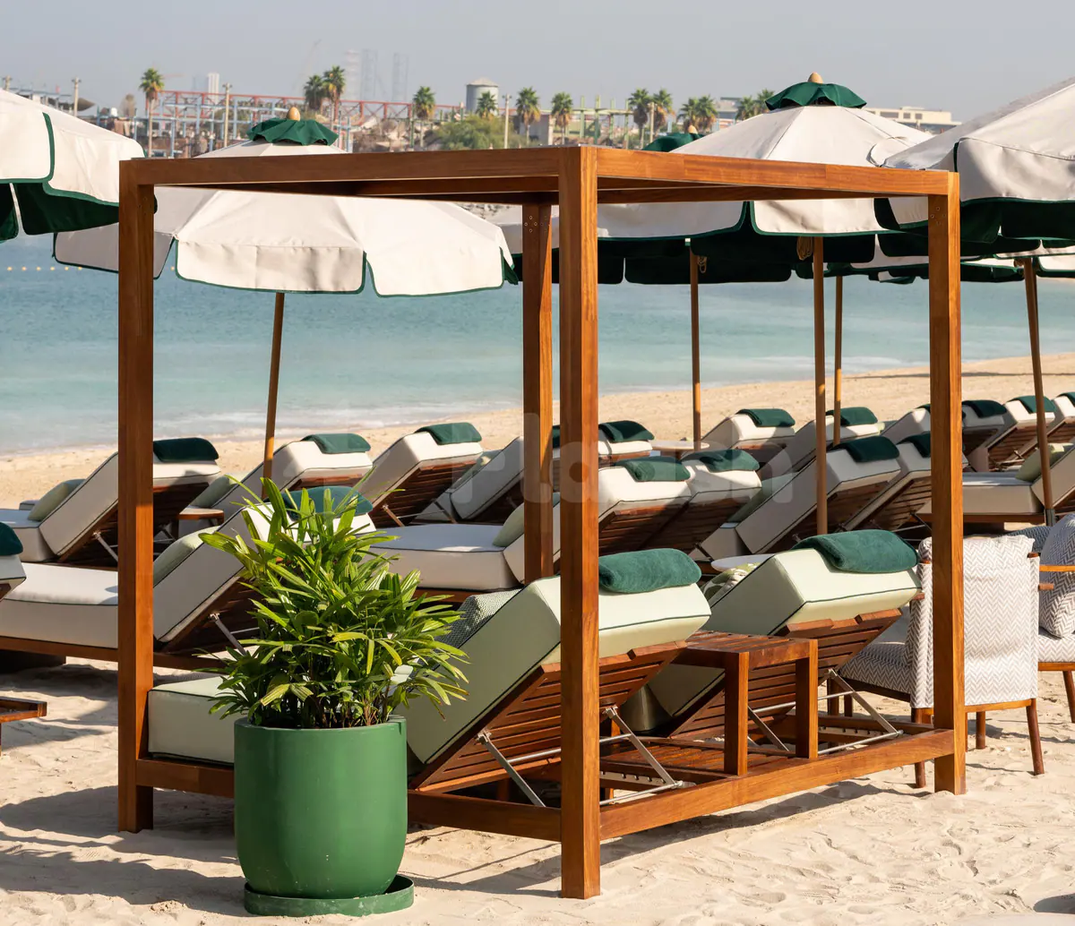 Wooden cabana structure at Baoli Restaurant Dubai terrace with lounge chairs and green potted plant overlooking the beach