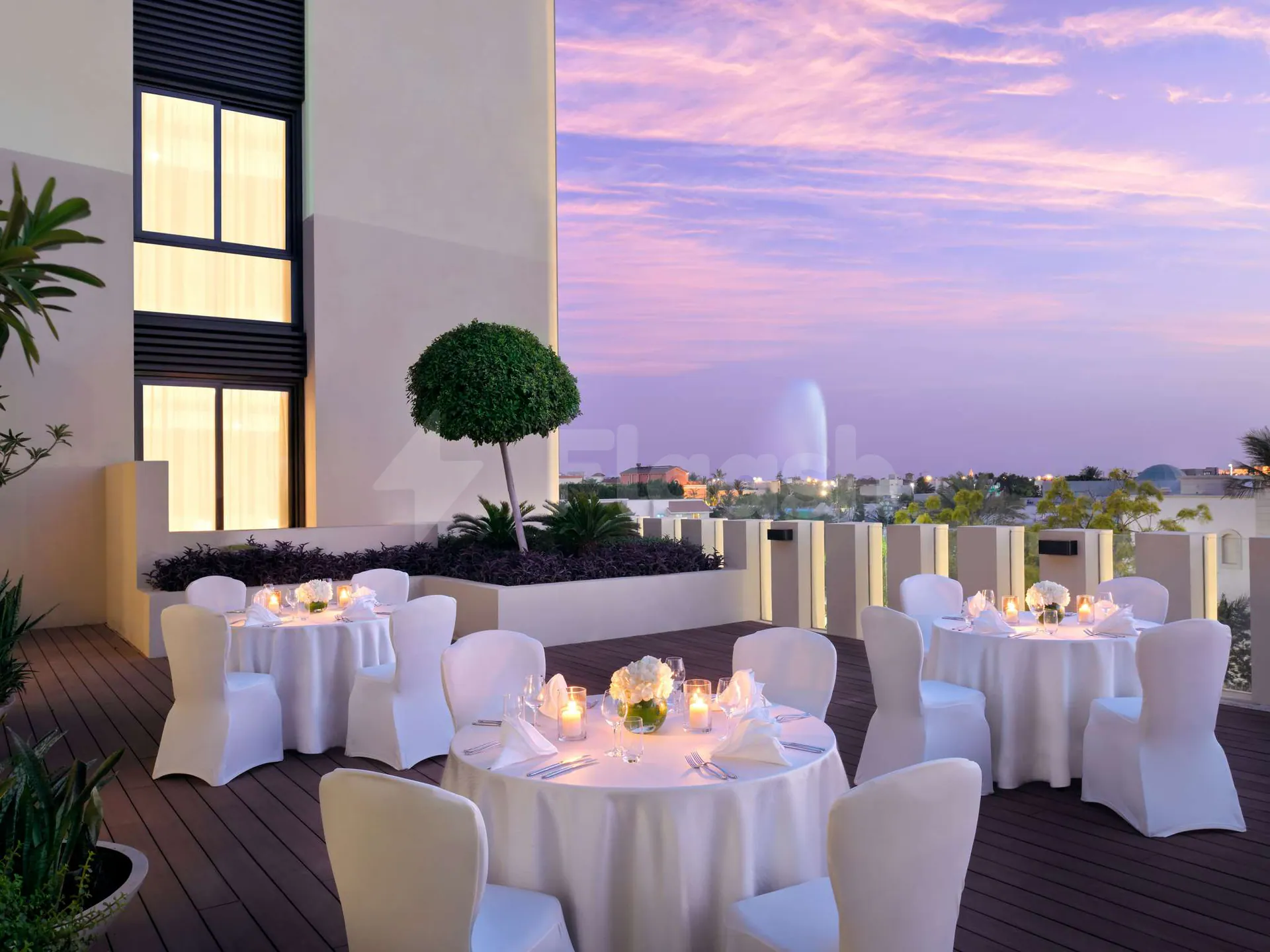 Rooftop terrace at Rasoi By Vineet Jeddah with white-draped tables, lit candles, and a distant fountain view