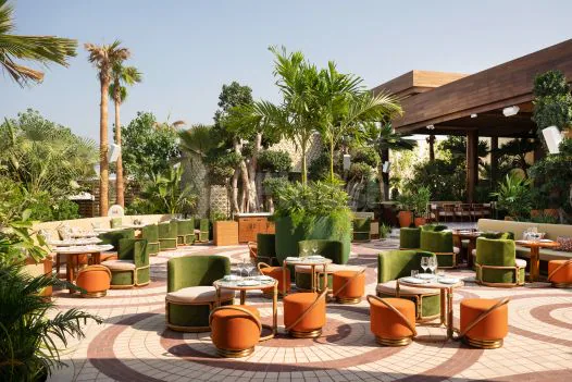 Rooftop terrace at Baoli Restaurant Dubai featuring a circular tiled floor and green velvet armchairs under a wooden