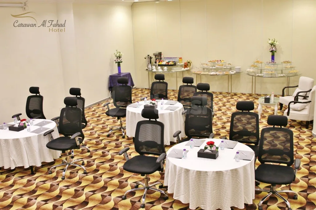 Meeting room at Carawan Al Fahad Hotel Riyadh with round tables, white tablecloths, black mesh-back chairs