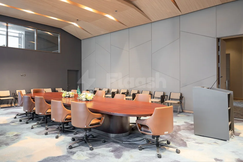Boardroom at Dhahran International Exhibition Center in Dammam featuring an oval wooden table, tan leather chairs, and grey