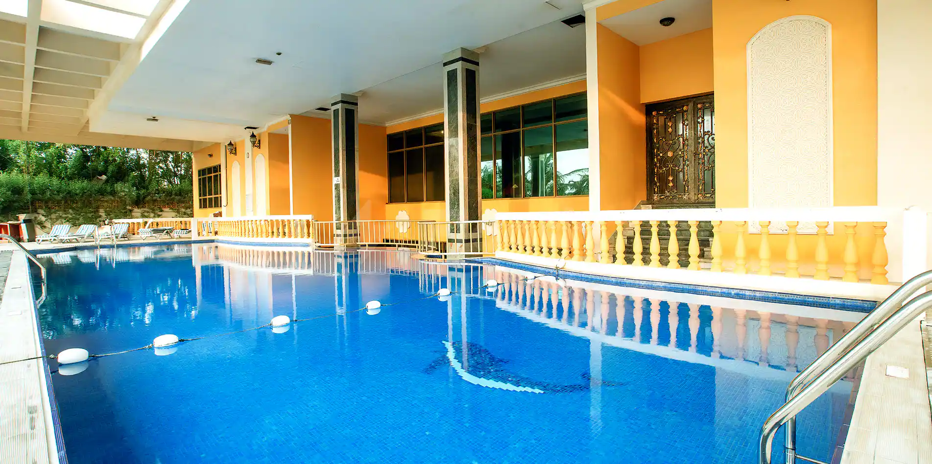 Indoor swimming pool at Sahara Beach Resort & Spa in Sharjah, featuring blue mosaic tiles and a yellow balustrade