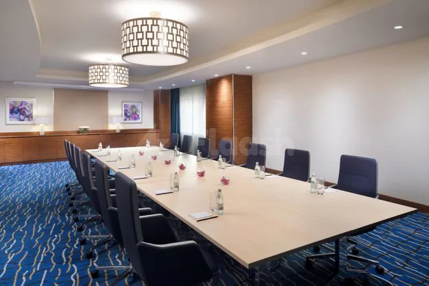 Boardroom at Marriott Executive Apartments Al Khobar featuring a long wooden table, black chairs, blue patterned carpet