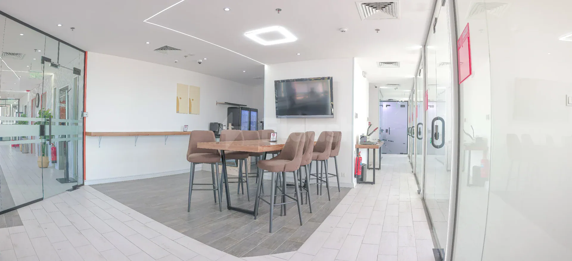 Restaurant area at Vision Work Space Jeddah featuring a high wooden table with brown upholstered stools