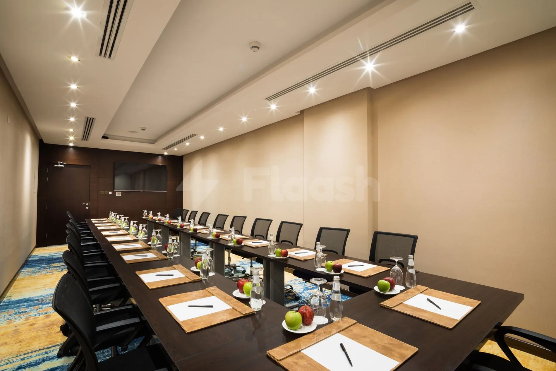 Boardroom at Naviti By Warwick Dammam with a long dark wooden table, black mesh chairs, and fruit-plated place