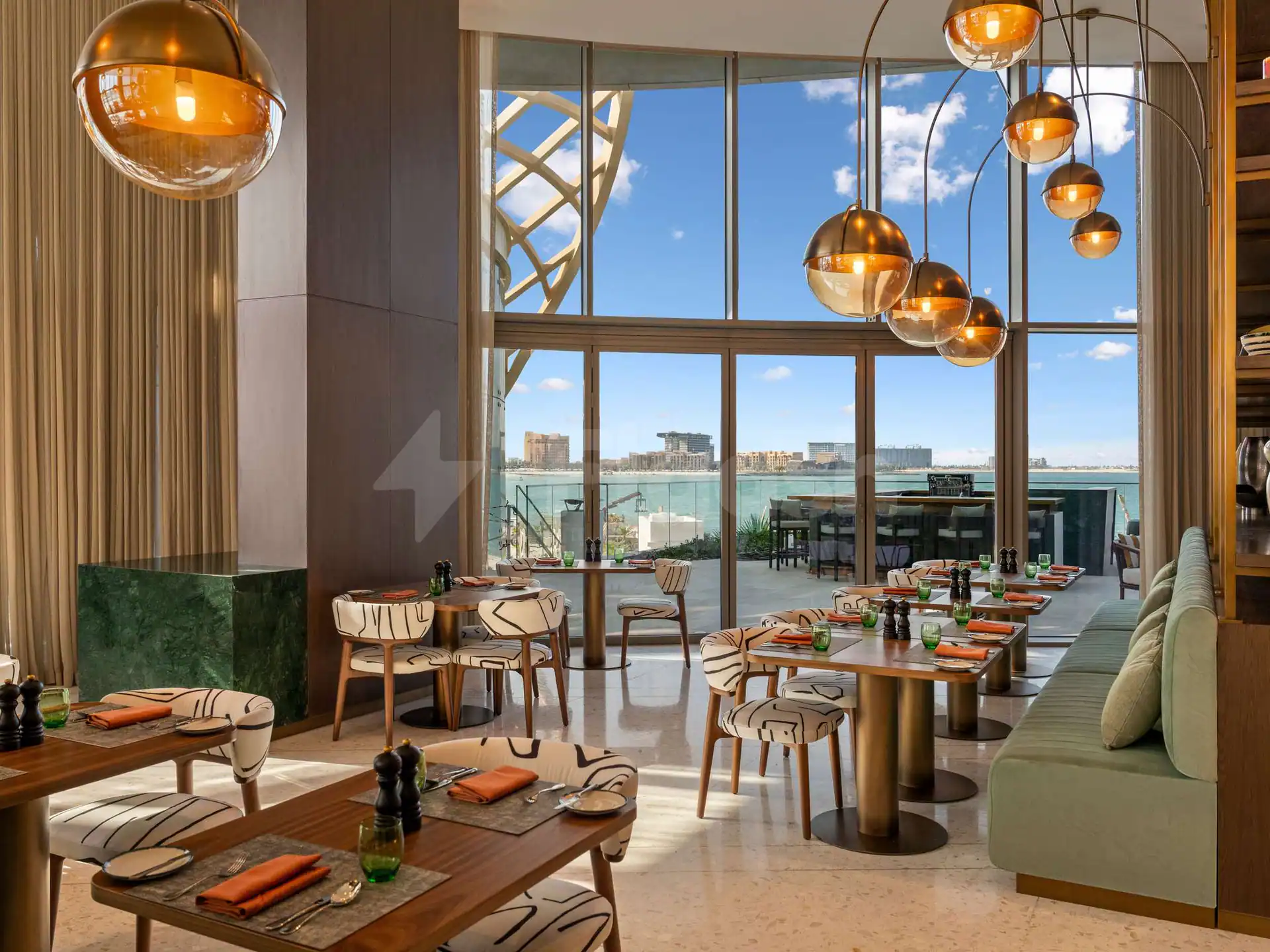 Restaurant at SO Ras Al Khaimah Hotel & Resort with brass pendant lights and large windows overlooking the sea